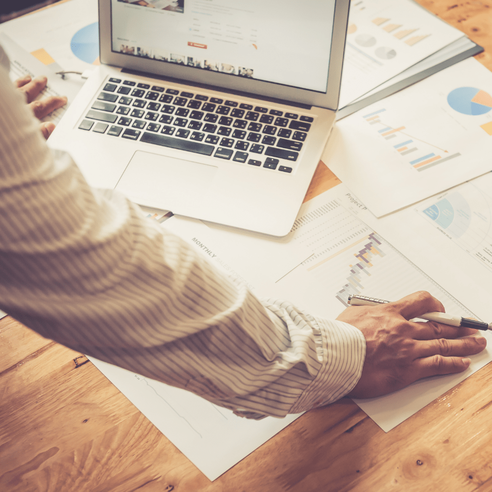 Image of a man over a laptop and printed report