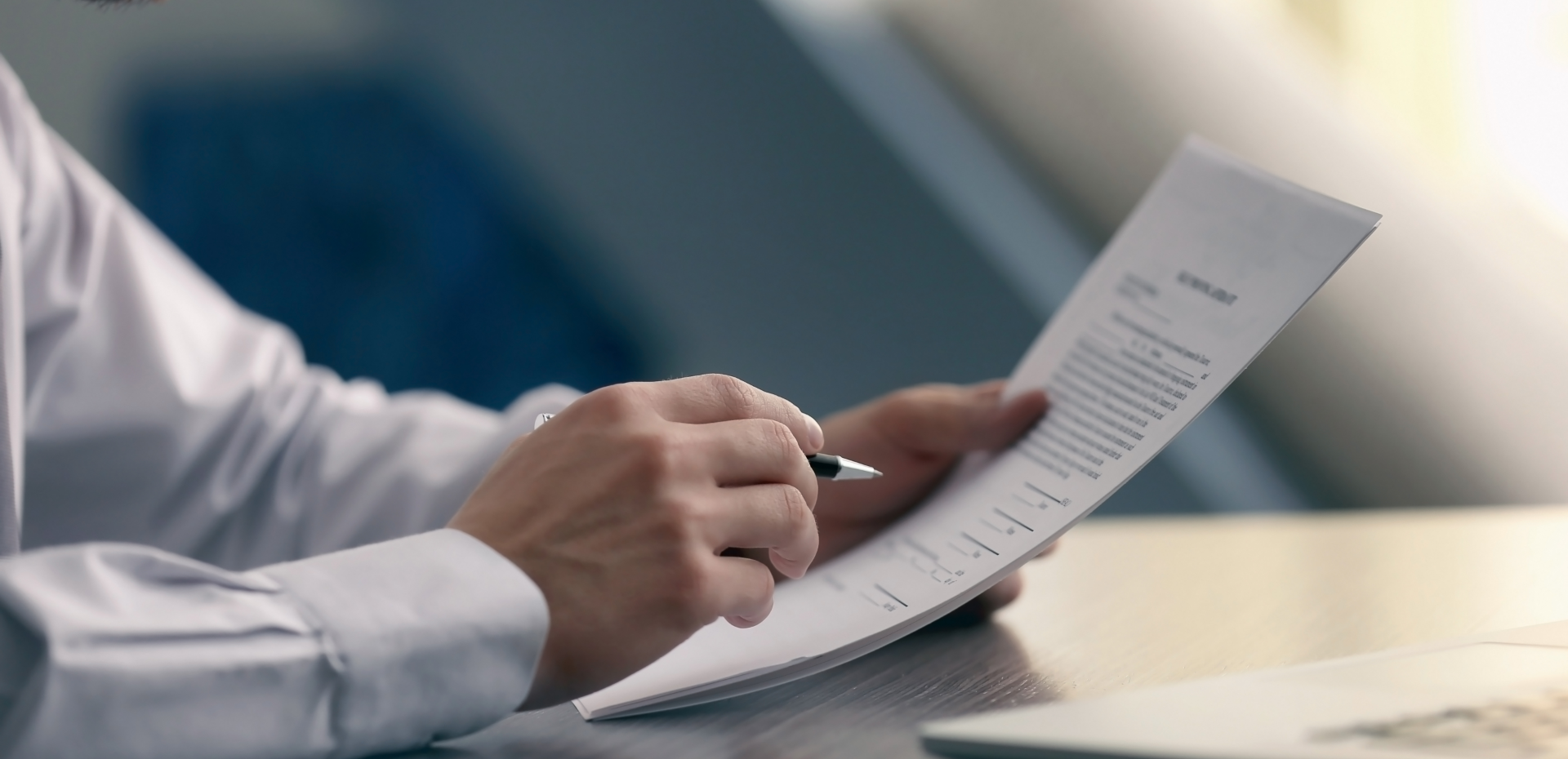 Image of a man's hand holding a paper and a pen