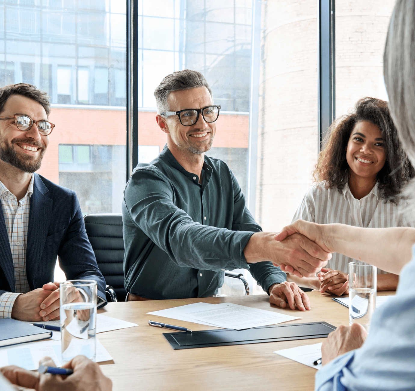 Image showing happy people in an office shaking hands over a conference table